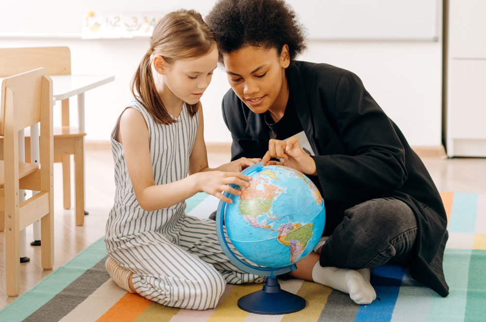 A woman and a girl look at a globe.